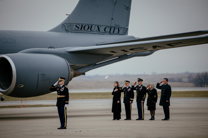 Four people stand in a line in front of a U.S. Air Force plane, saluting. 