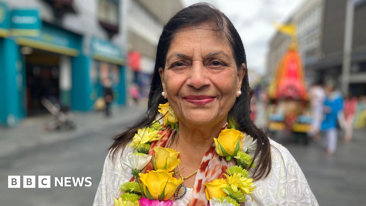 Manjula Sood stood in a city street. She has long dark hair and is wearing a necklace made of flowers.
