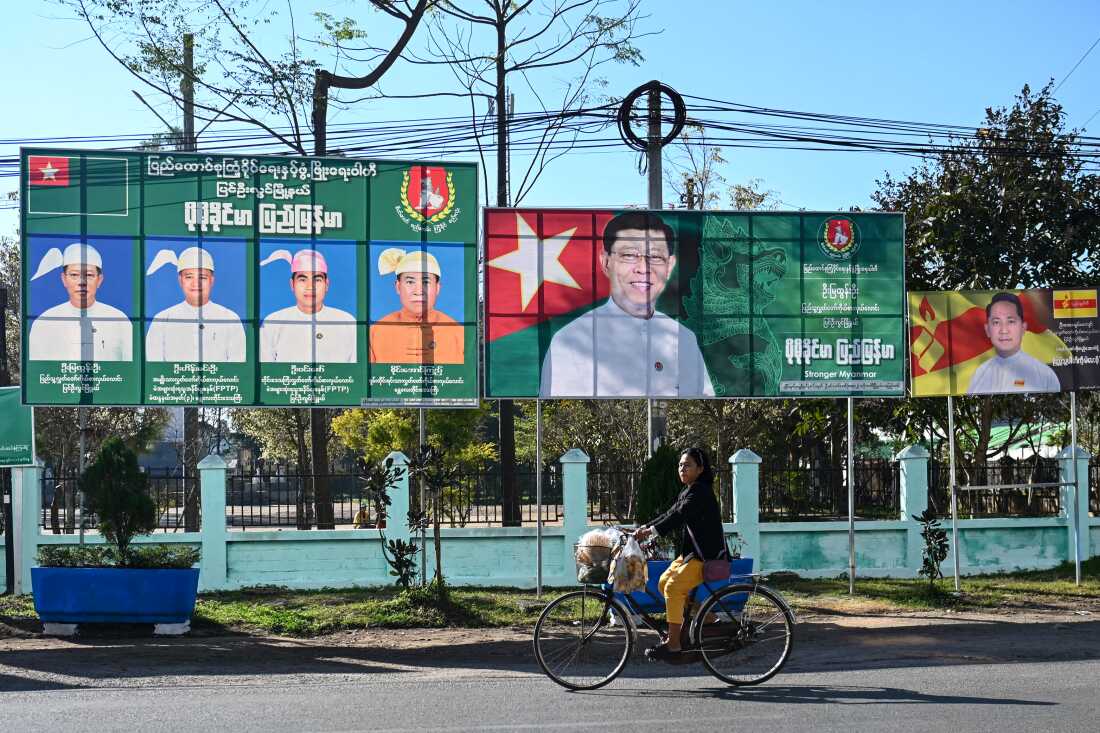 A woman rides past campaign billboards ahead of Myanmar's general election in Pyin Oo Lwin in Myanmar's Mandalay region. Myanmar's military has promised a phased election to begin Dec. 28.