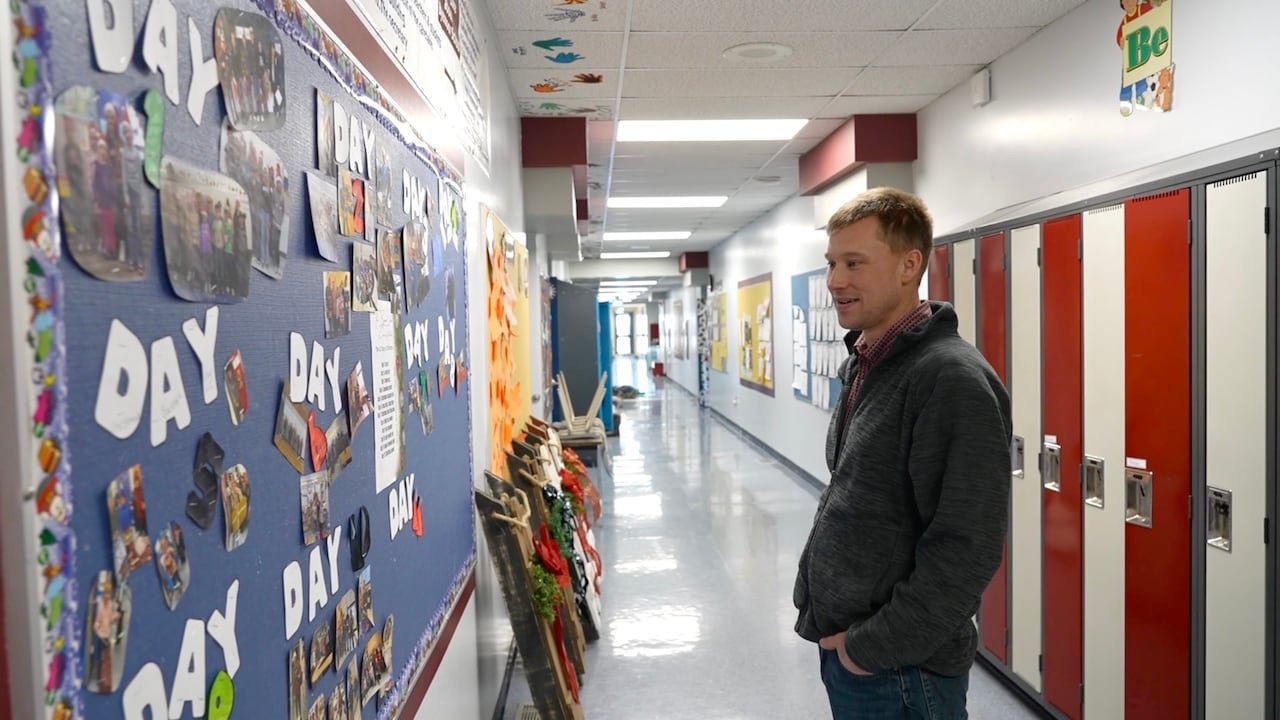 Man looking at a bulettin board in a school hallway