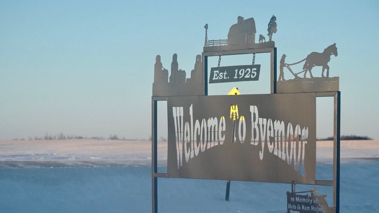 A welcome sign along the road, snow in the background