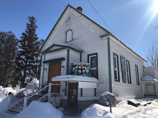 A white church with green panelling covered in snow