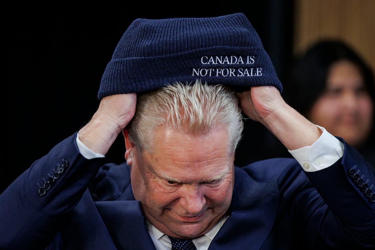 A man putting on a tuque that says on the front: Canada is Not for Sale
