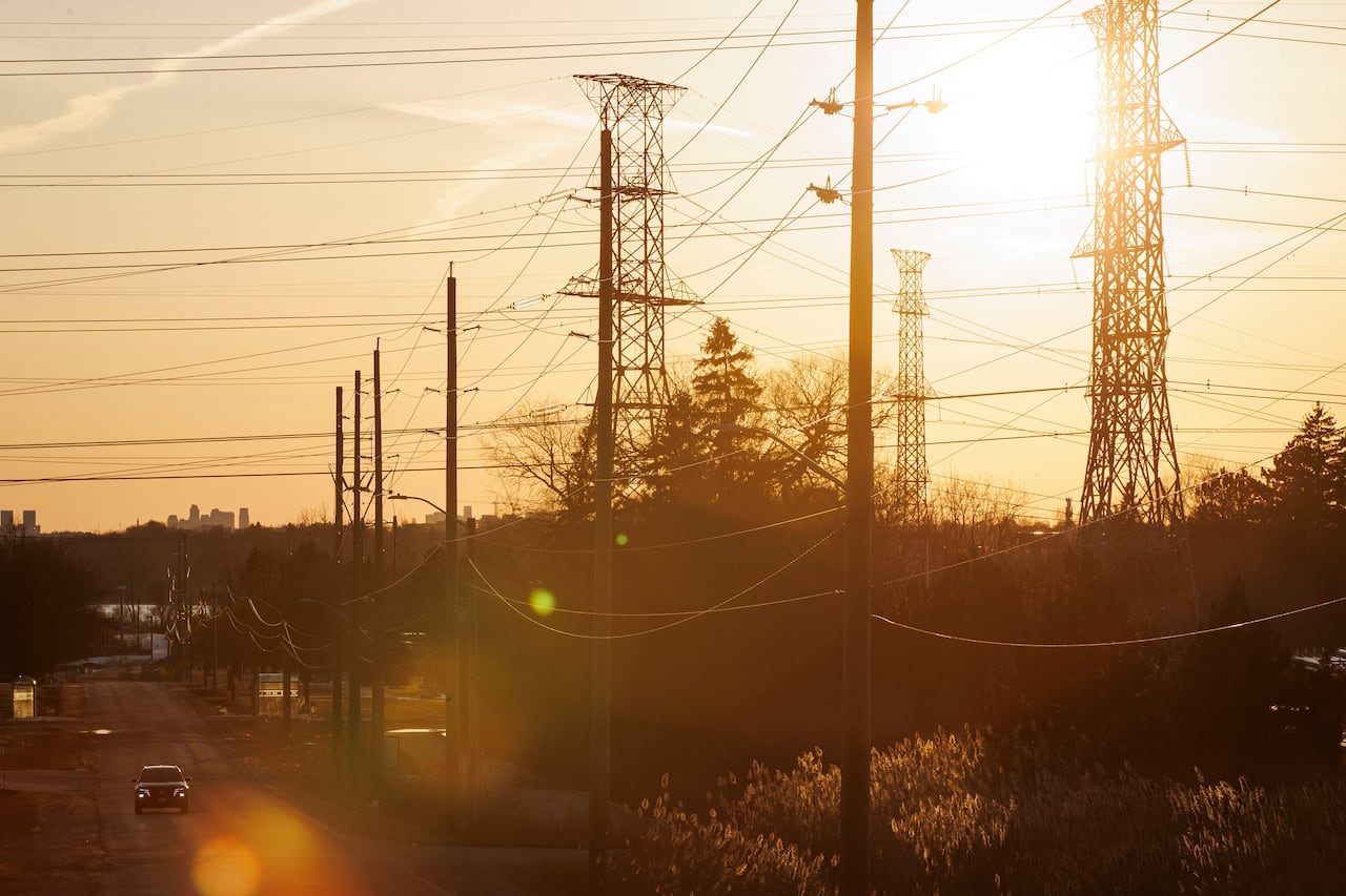 A car moving on a road, adjacent to power lines during golden light.