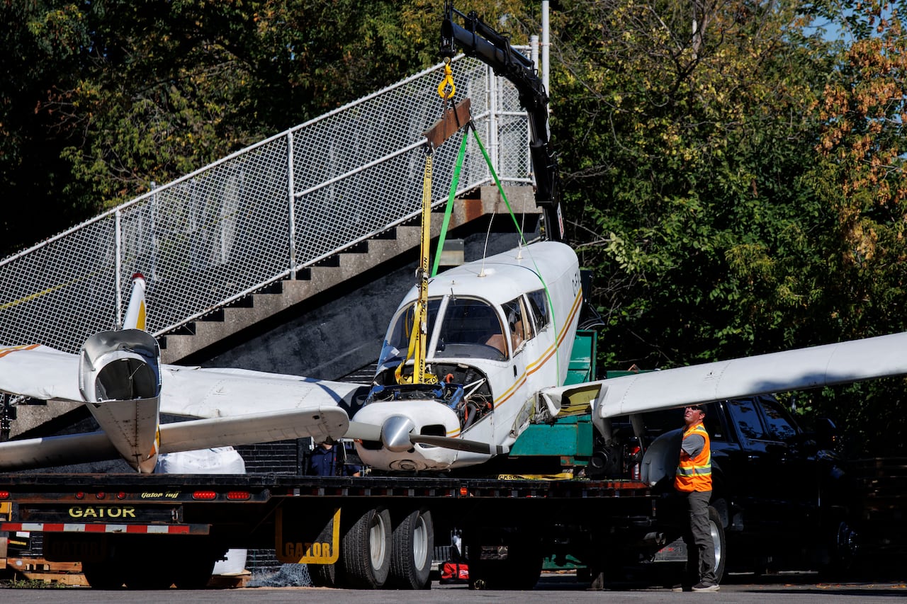 A plane that crashed at a soccer field is being lifted onto the back of a flat bedtruck.