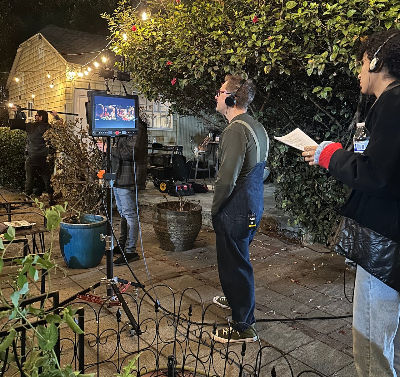 A man stands watching a tv monitor