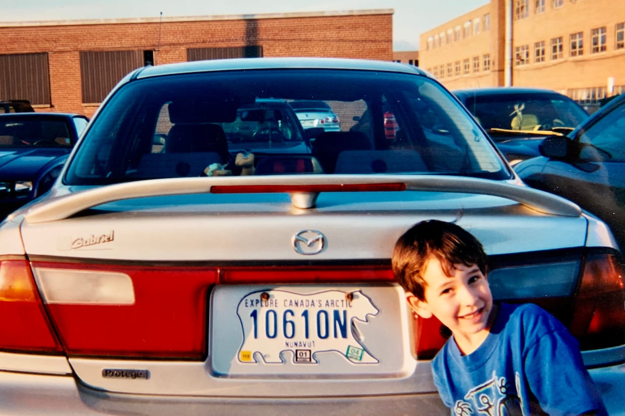 A child poses with a polar bear licence plate. 