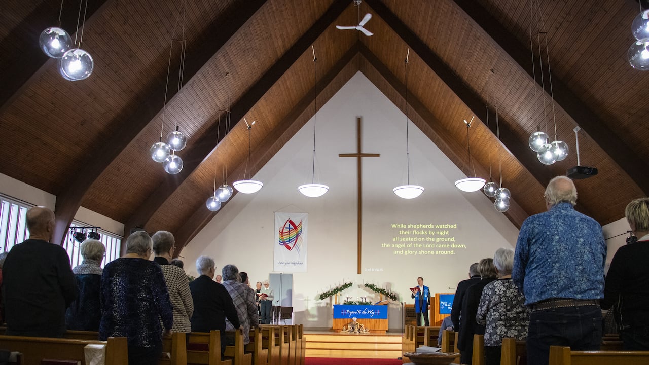 A minister leads a congregation in song.