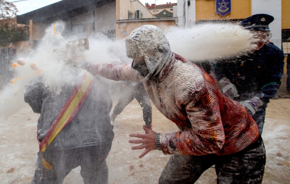 Revellers take part in the Els Enfarinats festival, a battle using flour, eggs and firecrackers, in the town of Ibi near Alicante, Spain, Sunday Dec. 28, 2025. (AP Photo/Alberto Saiz)