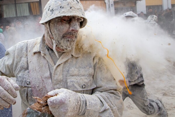 Revellers take part in the Els Enfarinats festival, a battle using flour, eggs and firecrackers, in the town of Ibi near Alicante, Spain, Sunday Dec. 28, 2025. (AP Photo/Alberto Saiz)