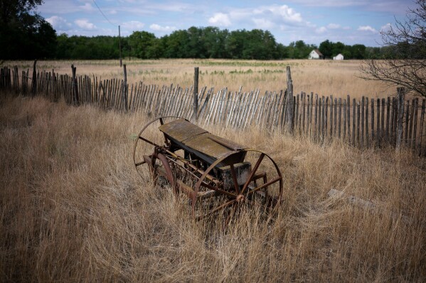 An abandoned plow sits on parched land in Kiskunmajsa, Hungary, Monday, July 28, 2025. (AP Photo/Denes Erdos)