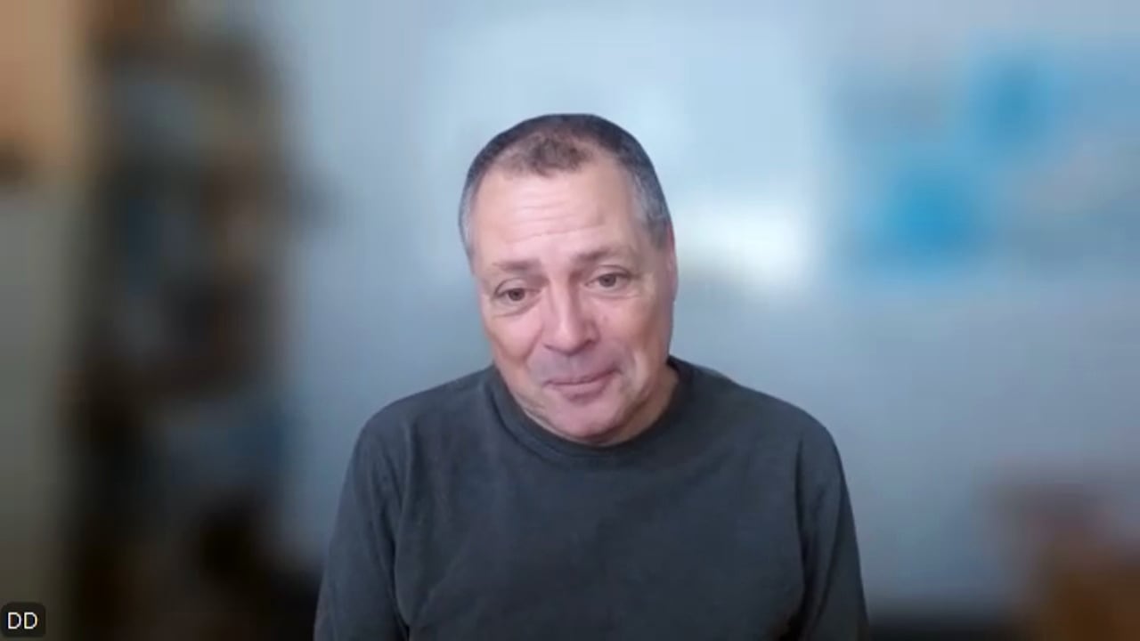 An image of Daniel from a Zoom interview with the background blurred. 