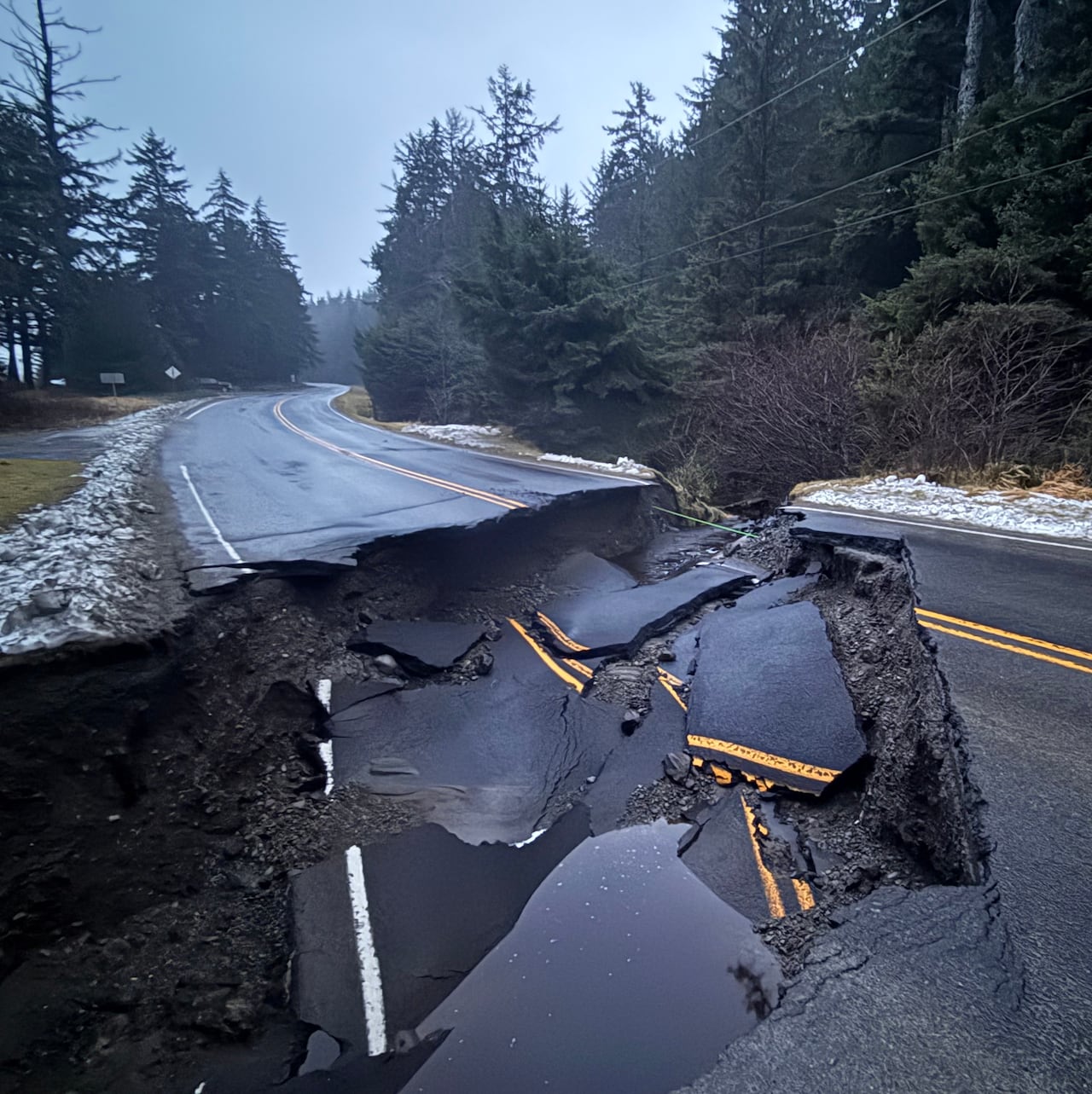 A heavily damaged road is seen on a cloudy day.