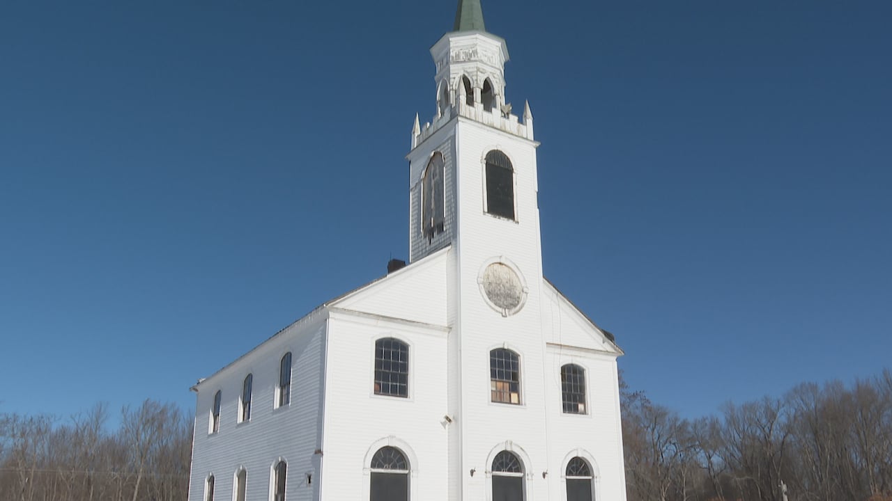 A white historic church building with several windows and a tower.
