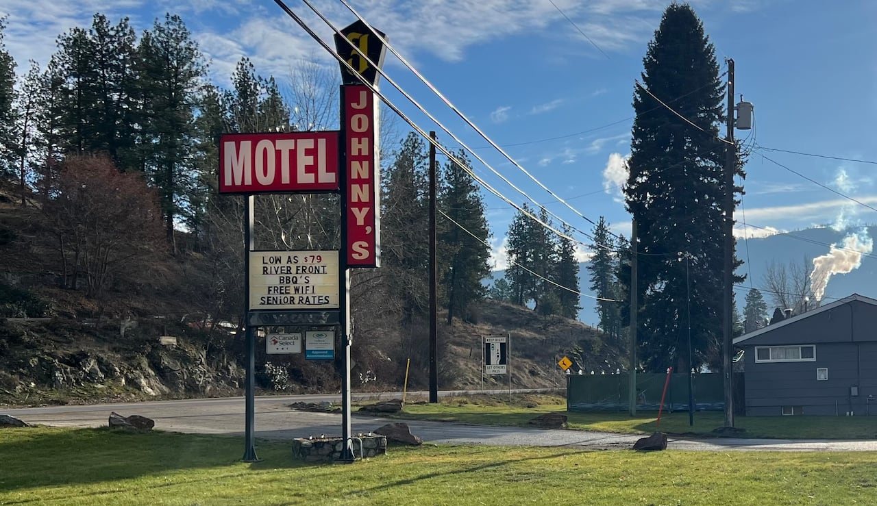 A motel sign on a sunny lawn. It reads 'Johnny's.' and advertises low prices.