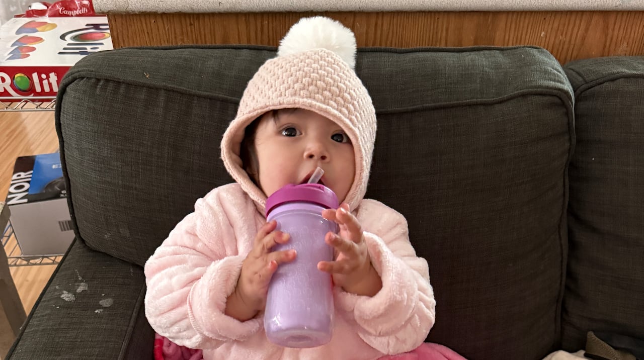 A girl is wearing layers of clothing while eating snacks.