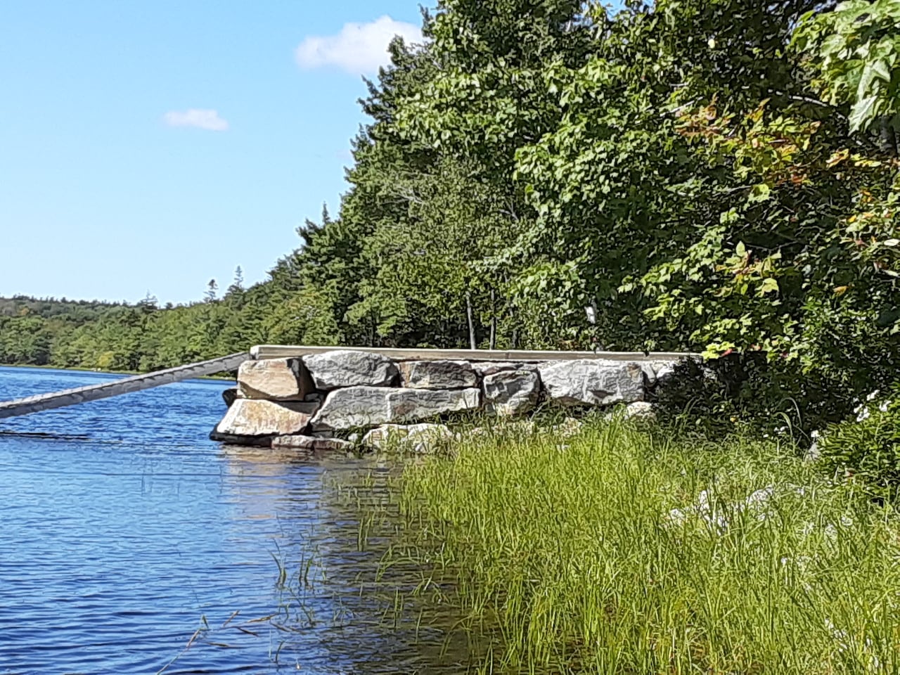 A dock atop a rock infill is shown in a lake.