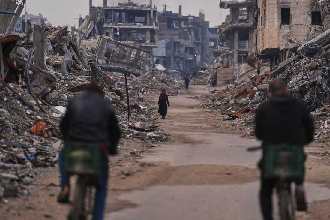A Palestinian woman walks along a street surrounded by buildings destroyed during Israeli air and ground operations in the Sheikh Radwan neighborhood, in Gaza City, Tuesday.