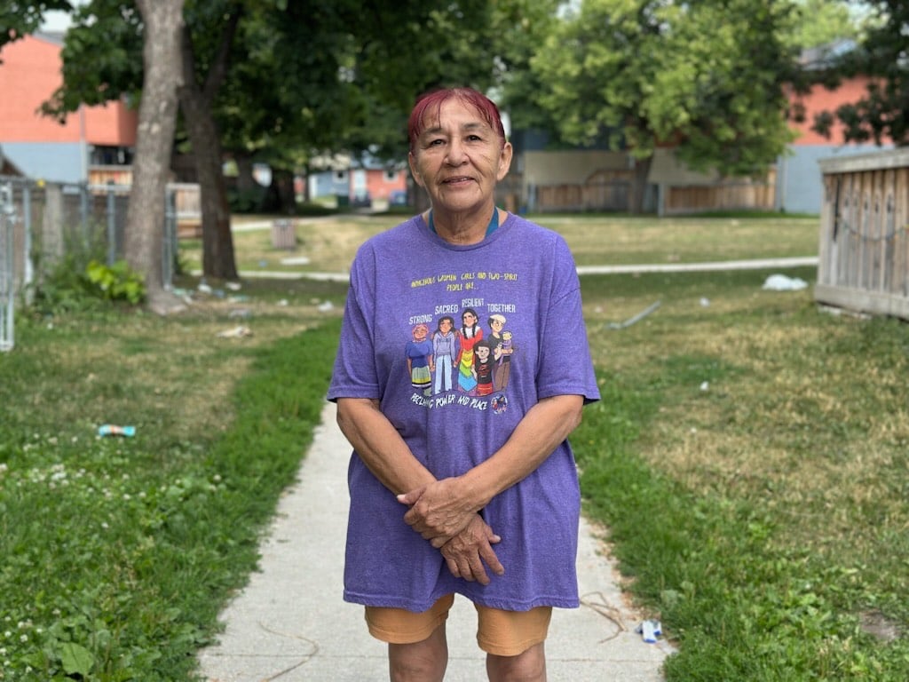 A woman in a purple T-shirt smiles.