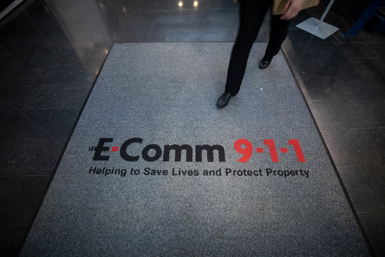 A person walks onto a mat with the words, 'E-Comm 91: Helping to save lives and protect property.'