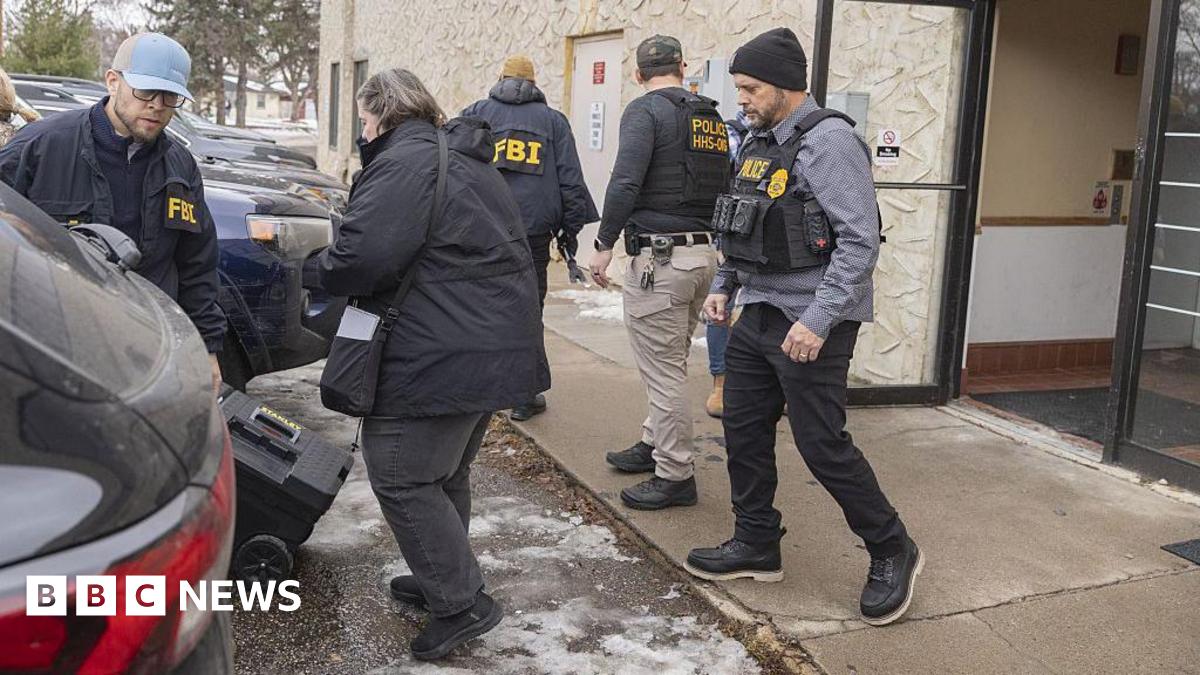 Agents with FBI and police jackets stand outside an office building