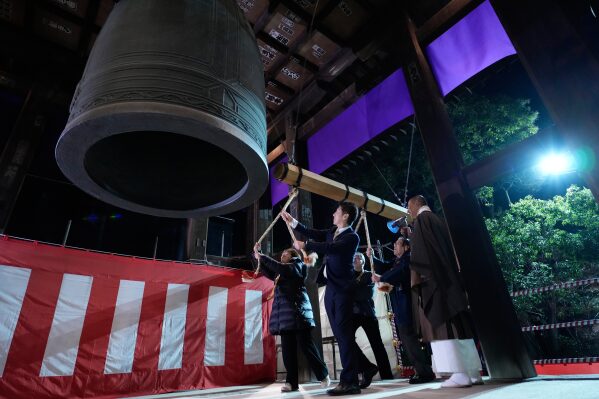 People strike a giant bell to celebrate the New Year at the Zojoji Buddhist temple, minutes after midnight Thursday Jan. 1, 2026, in Tokyo. (AP Photo/Eugene Hoshiko)