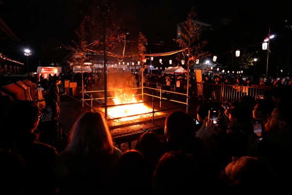 People burn old resolutions on the New Year at the Zojoji Buddhist temple, minutes after midnight Thursday Jan. 1, 2026, in Tokyo. (AP Photo/Eugene Hoshiko)