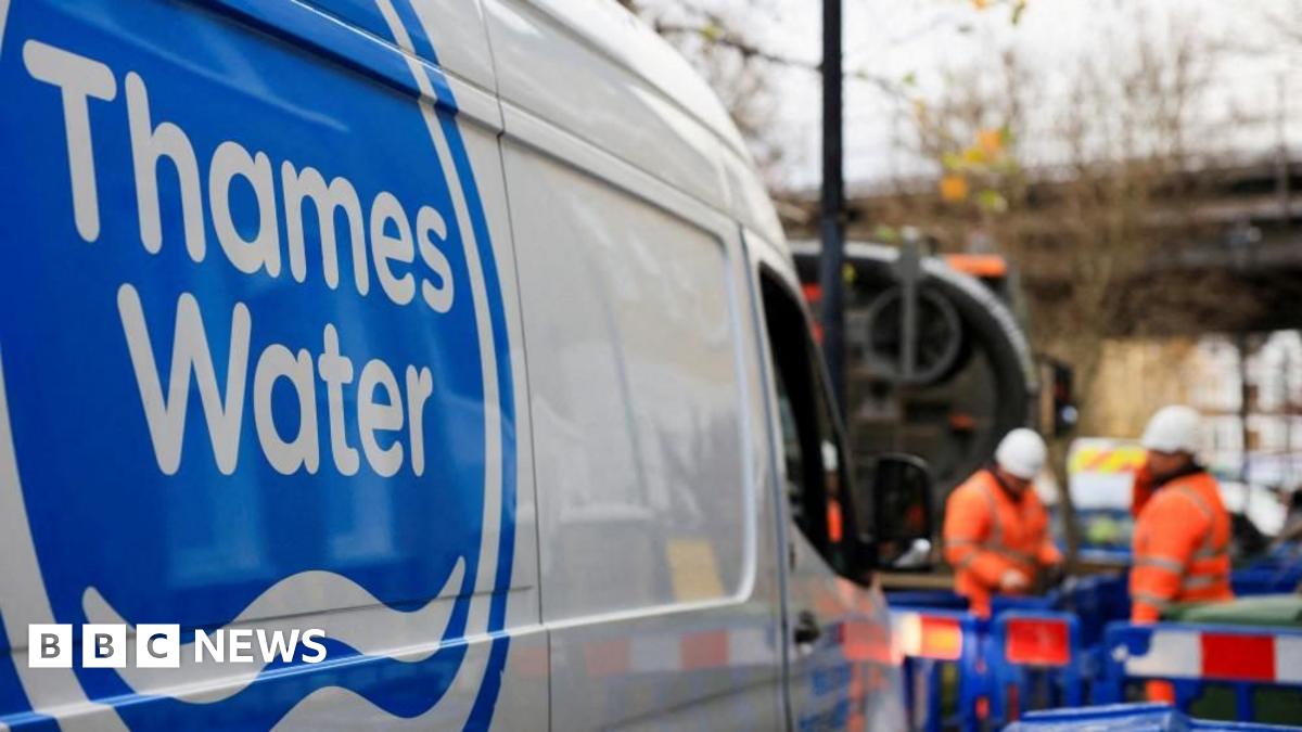 A white van with a blue and what Thames Water logo is parked in front of two workers standing in the background, who are wearing orange hi-vis jackets and white helmets.