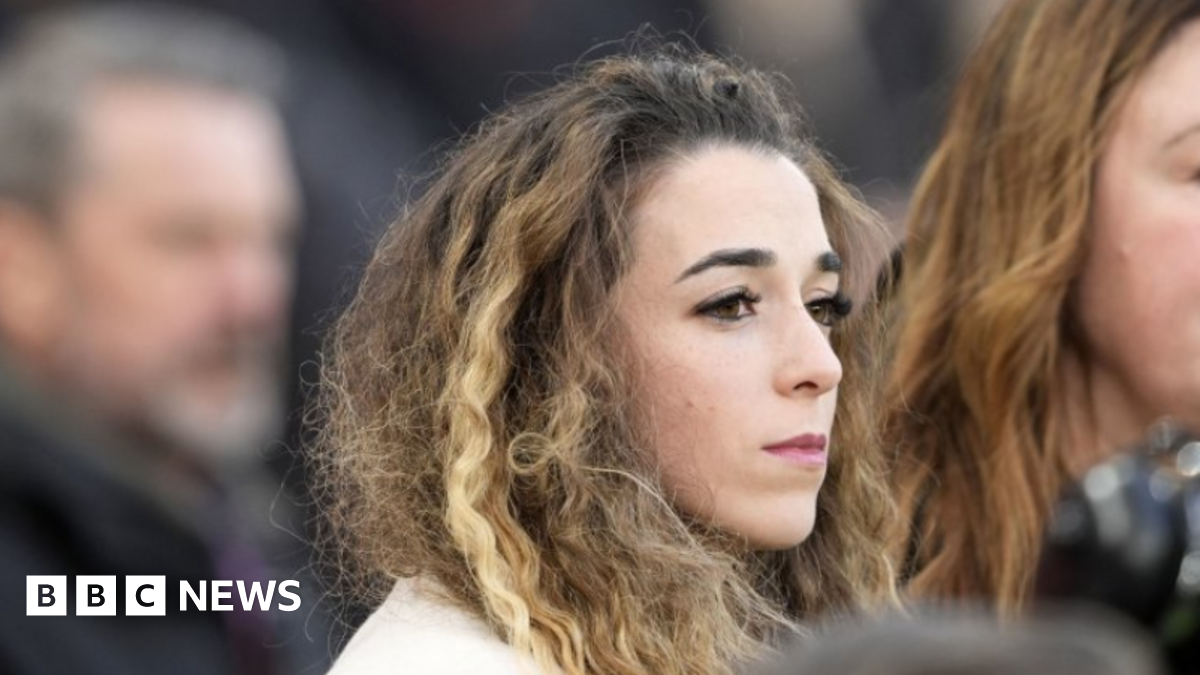 Jota's wife, wearing a white coat, looks out from the stands at Anfield as her two sons lead tributes to the Portugal forward