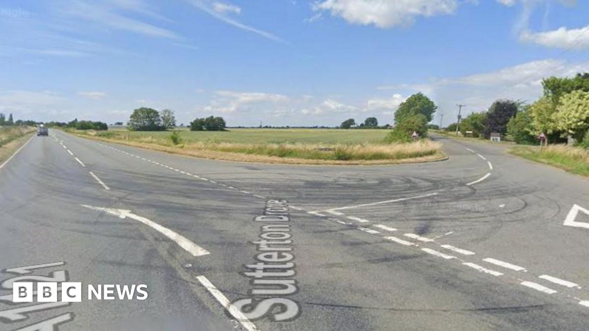 The junction of an 'A' road with a side road. Fields surround the roads.