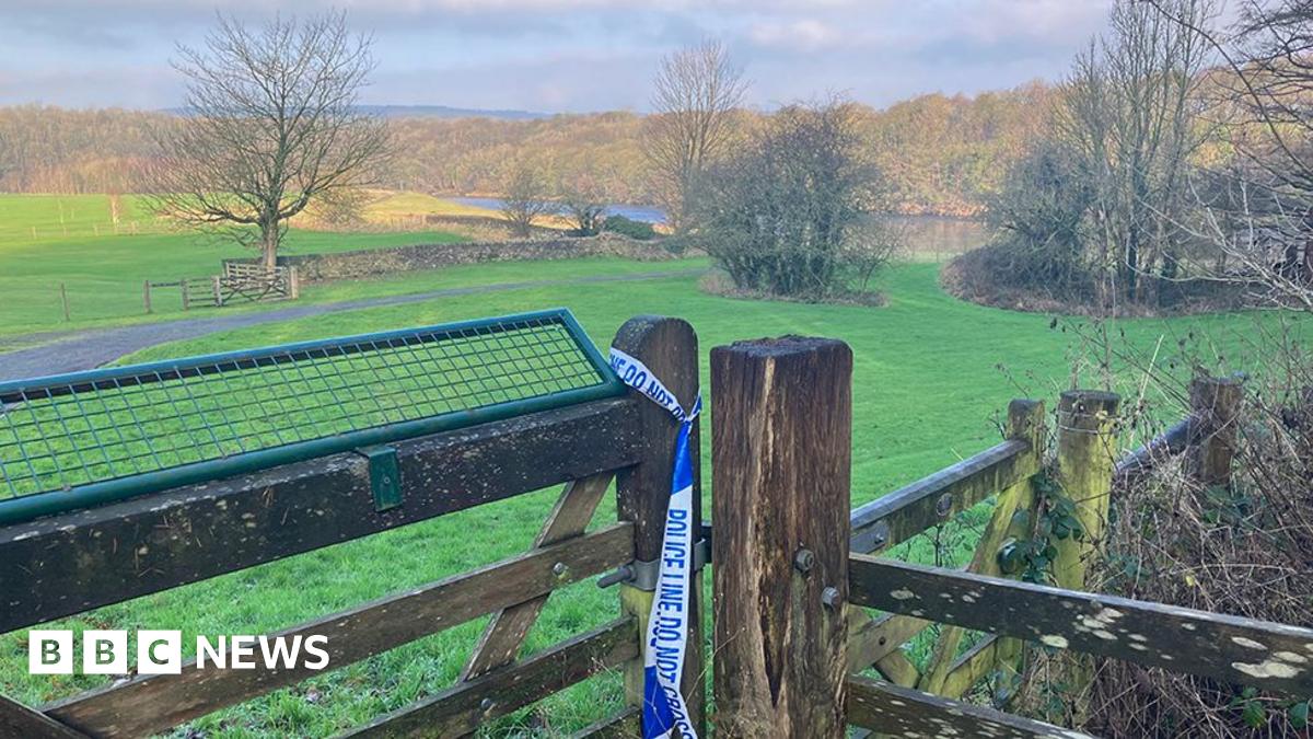 A view of the Ribble in the distance surrounded by countryside. In the foreground is a fence with police tape