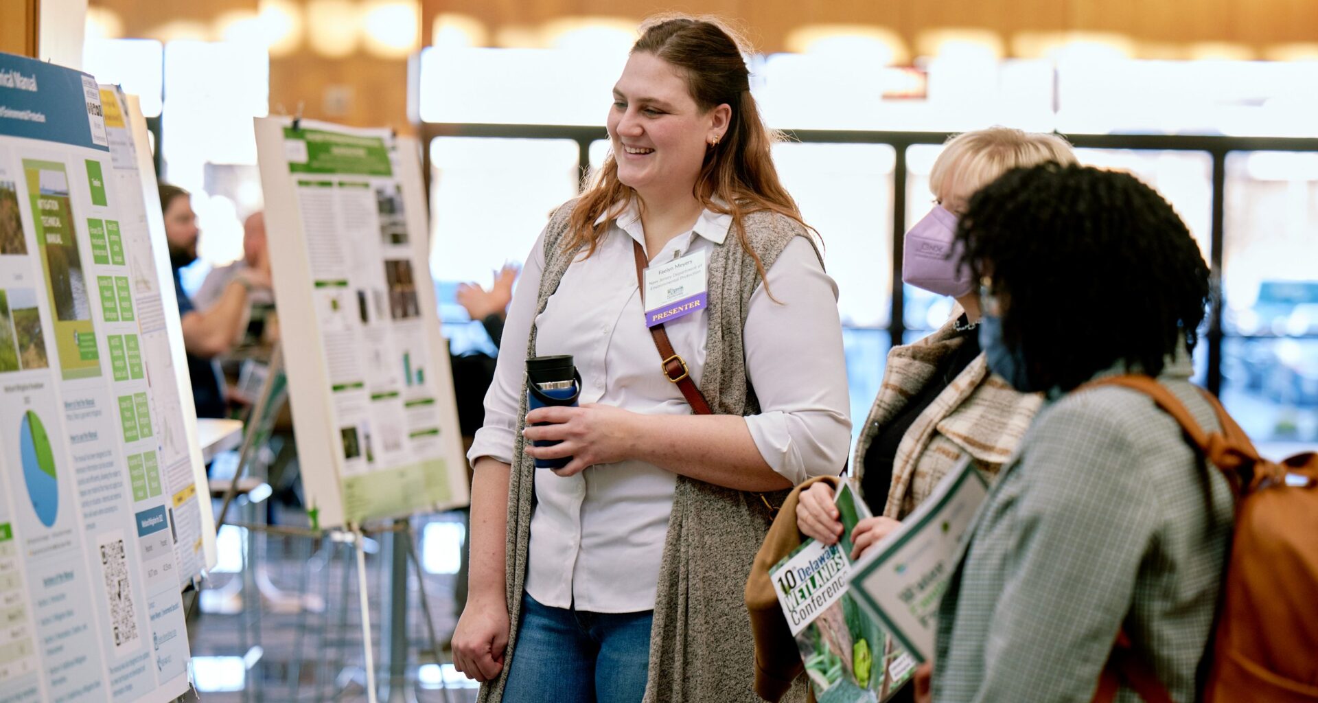 Three attendees at the 10th Delaware Wetlands Conference discuss the poster presentations in front of one poster.