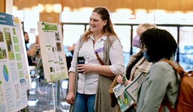 Three attendees at the 10th Delaware Wetlands Conference discuss the poster presentations in front of one poster.