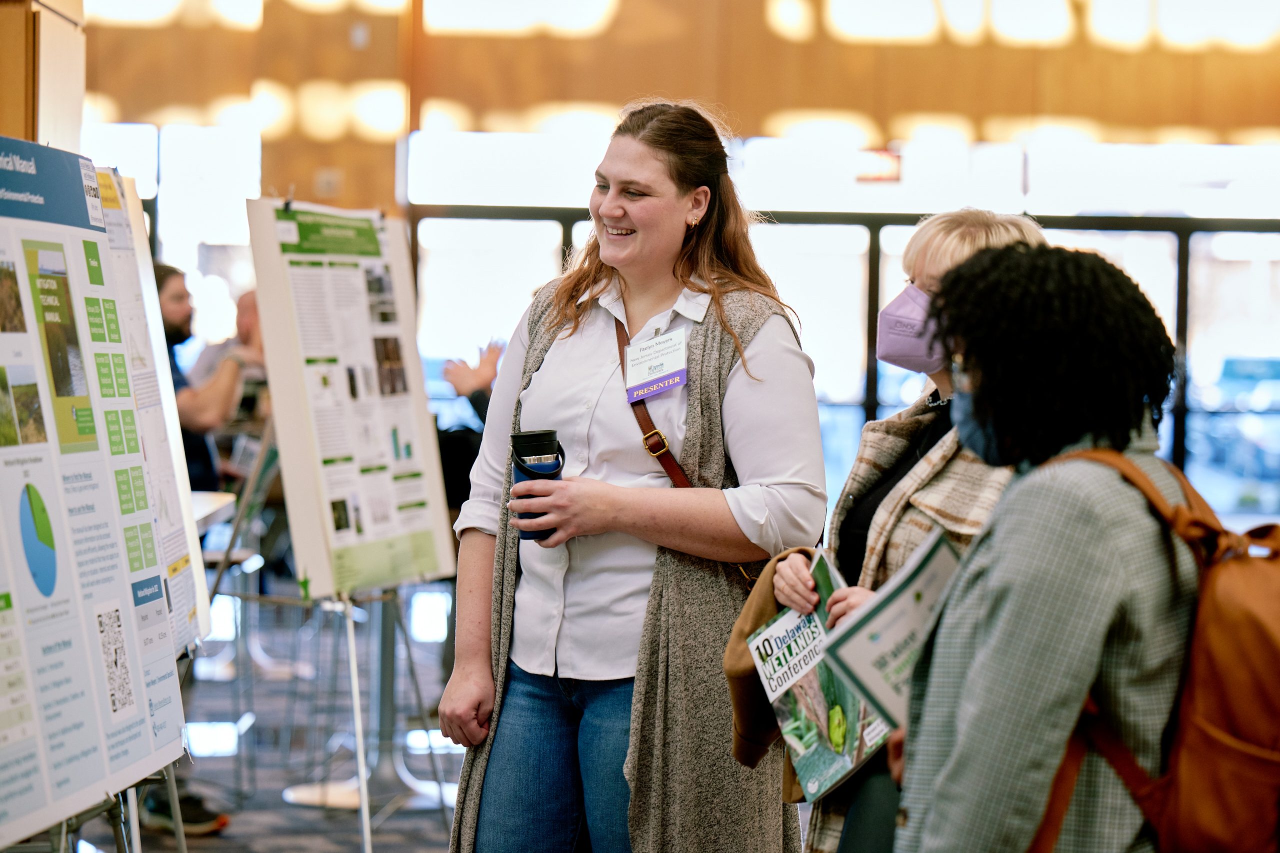 Three attendees at the 10th Delaware Wetlands Conference discuss the poster presentations in front of one poster.