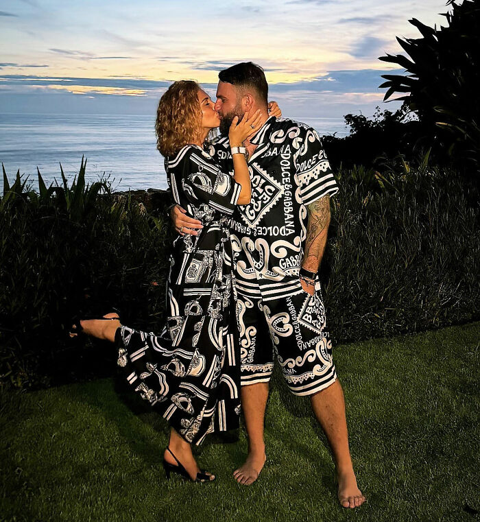 Couple in matching black and white outfits embracing outdoors near ocean at sunset, related to crypto scammer case.