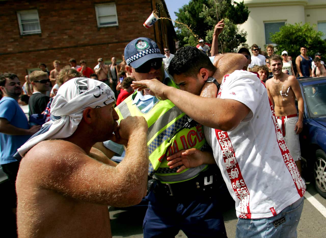 A shirtless man on the right attempts to punch a man in a white shirt.
