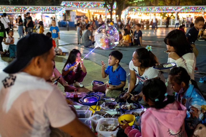 A family shares a meal during Christmas Eve at the Quezon Memorial Circle, in Quezon City, Metro Manila, on December 24, 2023.