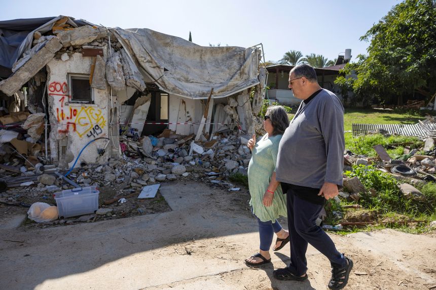 Ayelet Khon and Shar Shnurman walk past the remains of a home that was destroyed following the October 7 attack, in southern Israel, January 13, 2024.