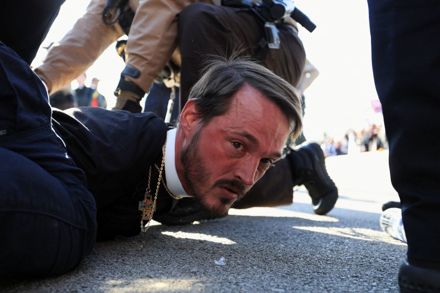 Pastor Michael Woolf, minister at Lake Street Church of Evanston, is detained by Illinois State Police during a protest outside the Broadview ICE facility in Chicago on November 14, 2025.
