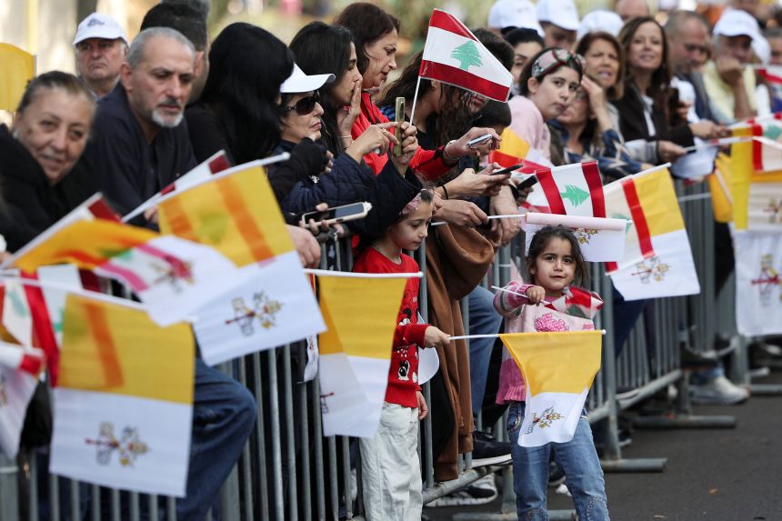 People holding Lebanese and Vatican flags gather in Baabda, Lebanon, as they await the arrival of Pope Leo on Sunday.