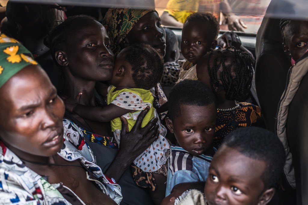 Women and children are packed tightly into the back of a car.