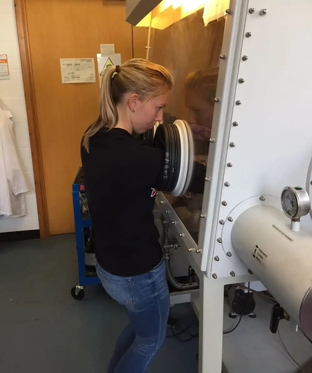 A side view of Taylor standing next to and using lab equipment.