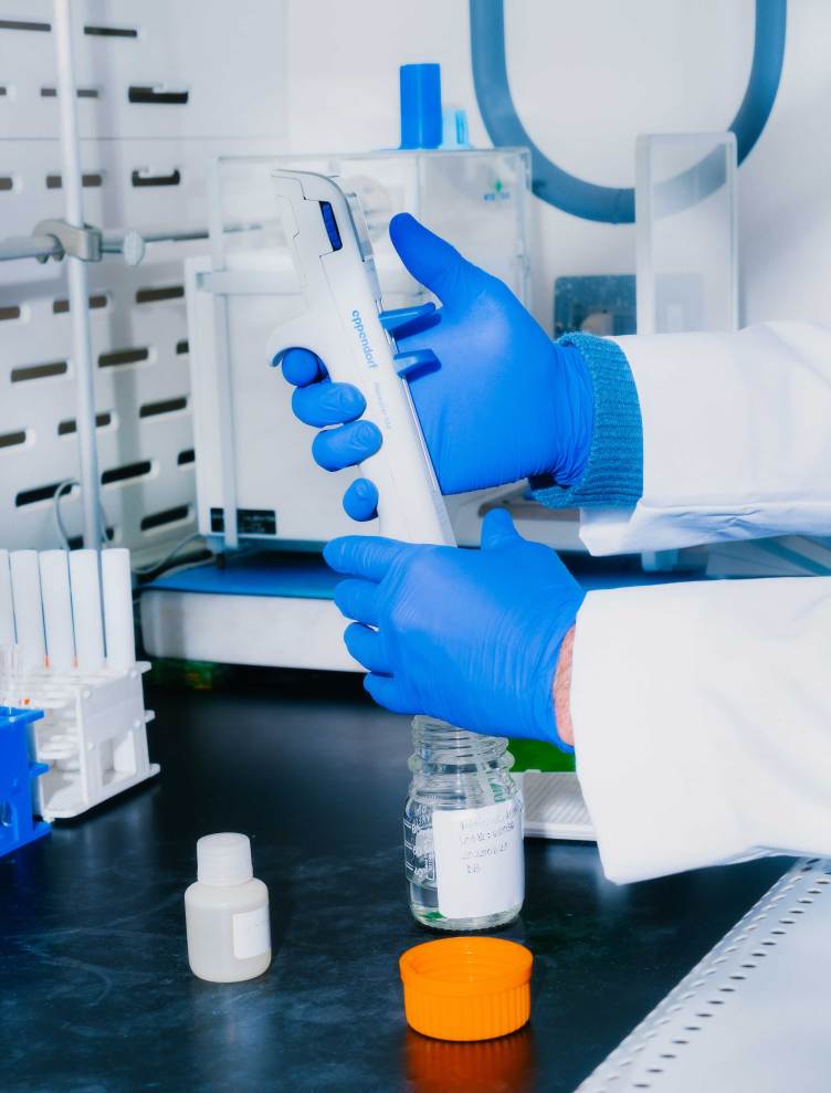 A lab technician dispenses a sample into a jar.