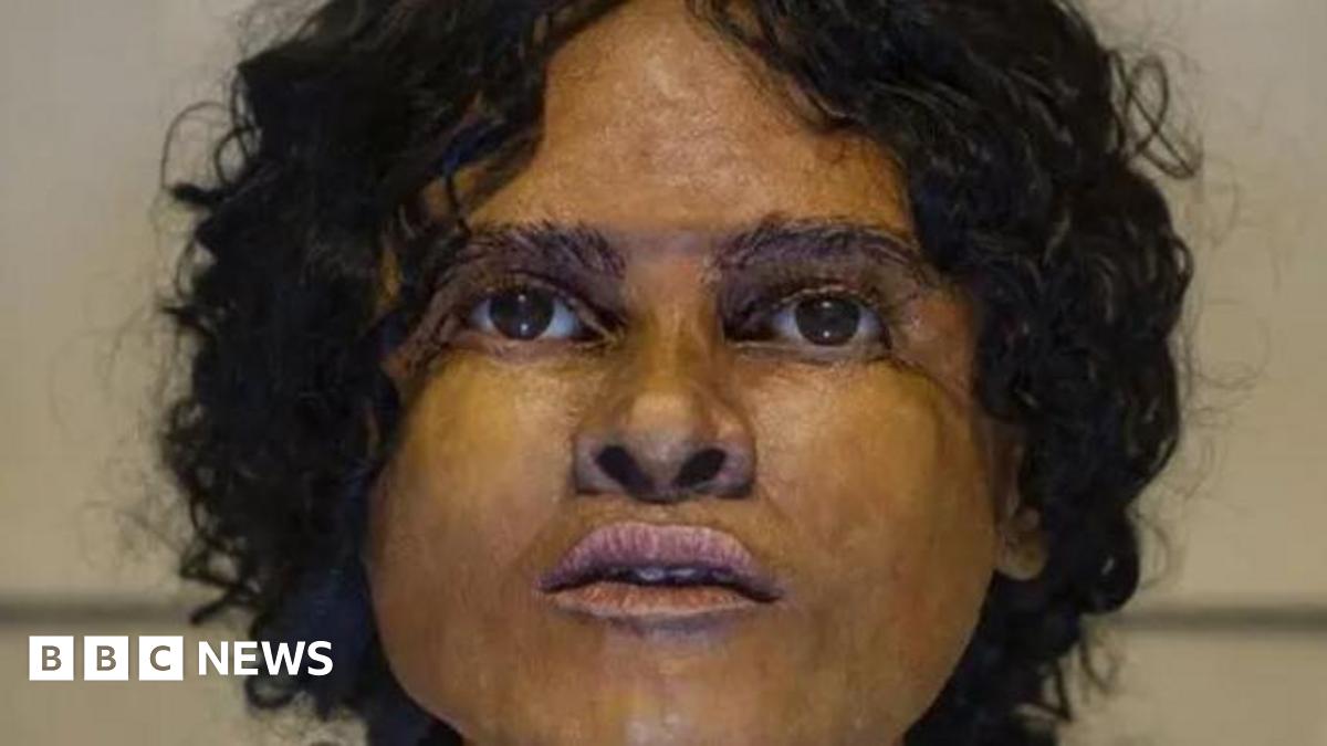 A woman. She has black curly hair and brown eyes.