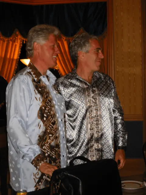 US Department of Justice Bill Clinton and Jeffrey Epstein stand closely together, looking right of the camera, both wearing paisley-print, silk shirts