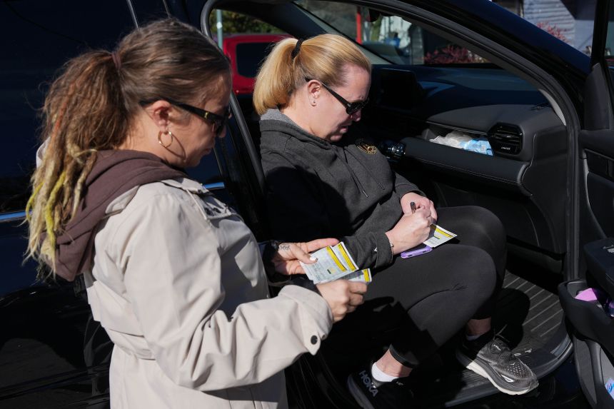 Christy Betz, right, writes rental assistance checks for Luna Pendelton, left, to distribute in Atlanta, GA, on December 16, 2025.