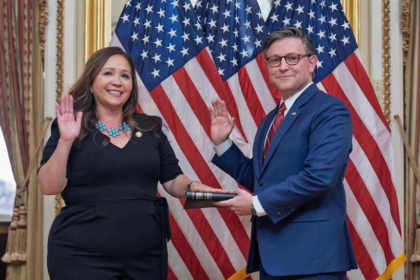 Adelita Grijalva puts her hand on a book held by Mike Johnson