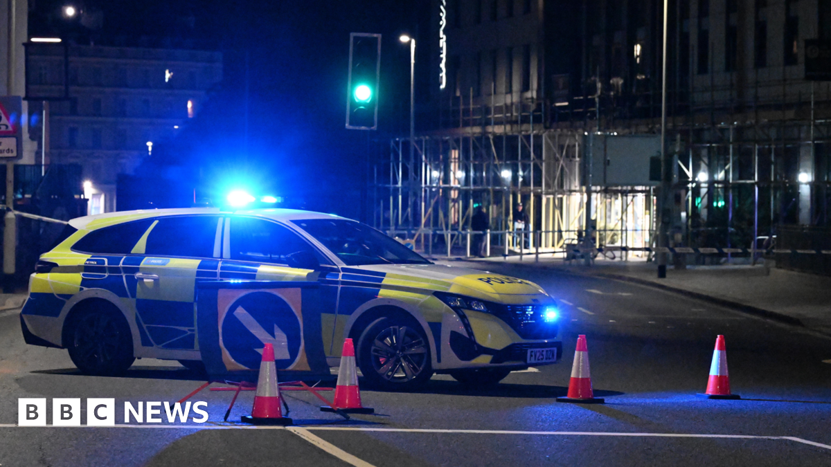 A police car is blocking a road off. It has its blue lights on.