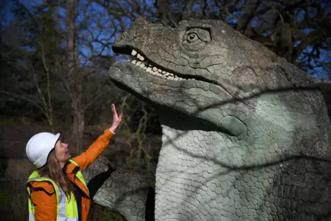 AFP via Getty Images An engineer studies one of the Crystal Palace Dinosaurs in Crystal Palace Park 