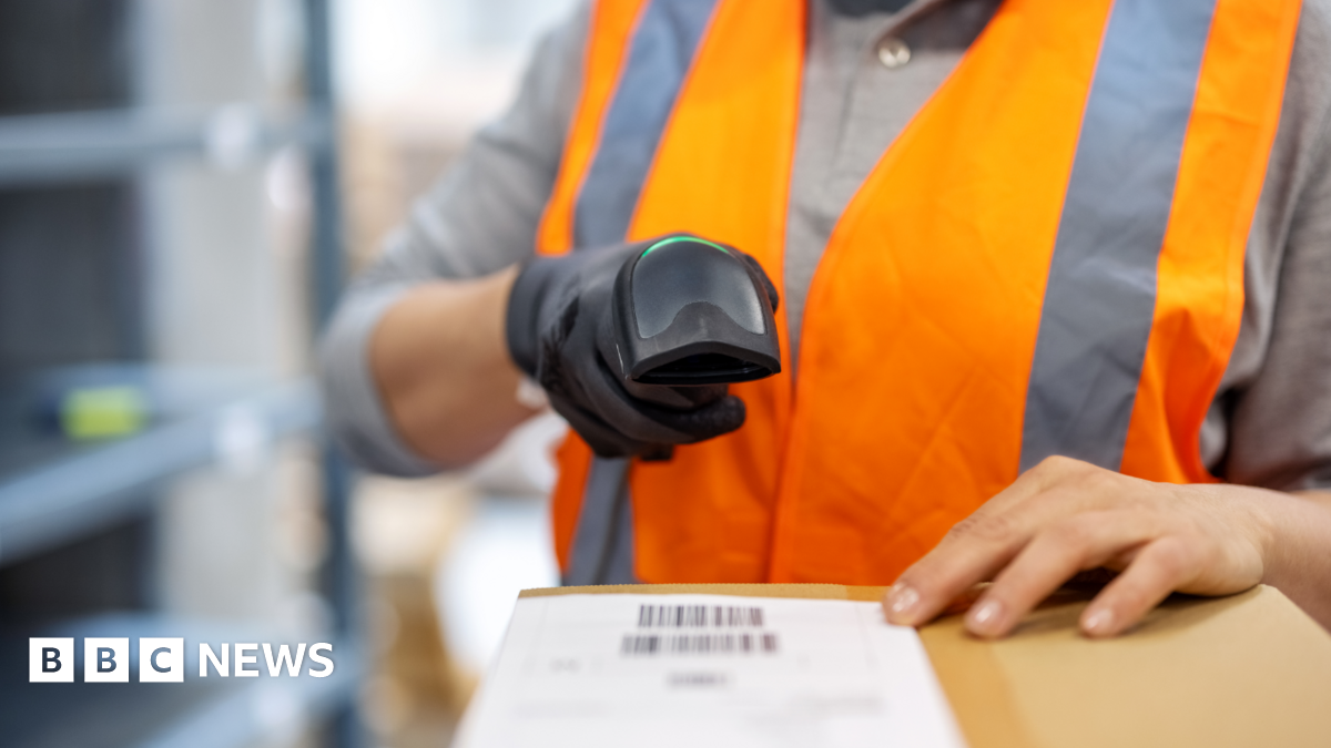 Close-up of an anonymous female warehouse worker scanning package with bar code scanner